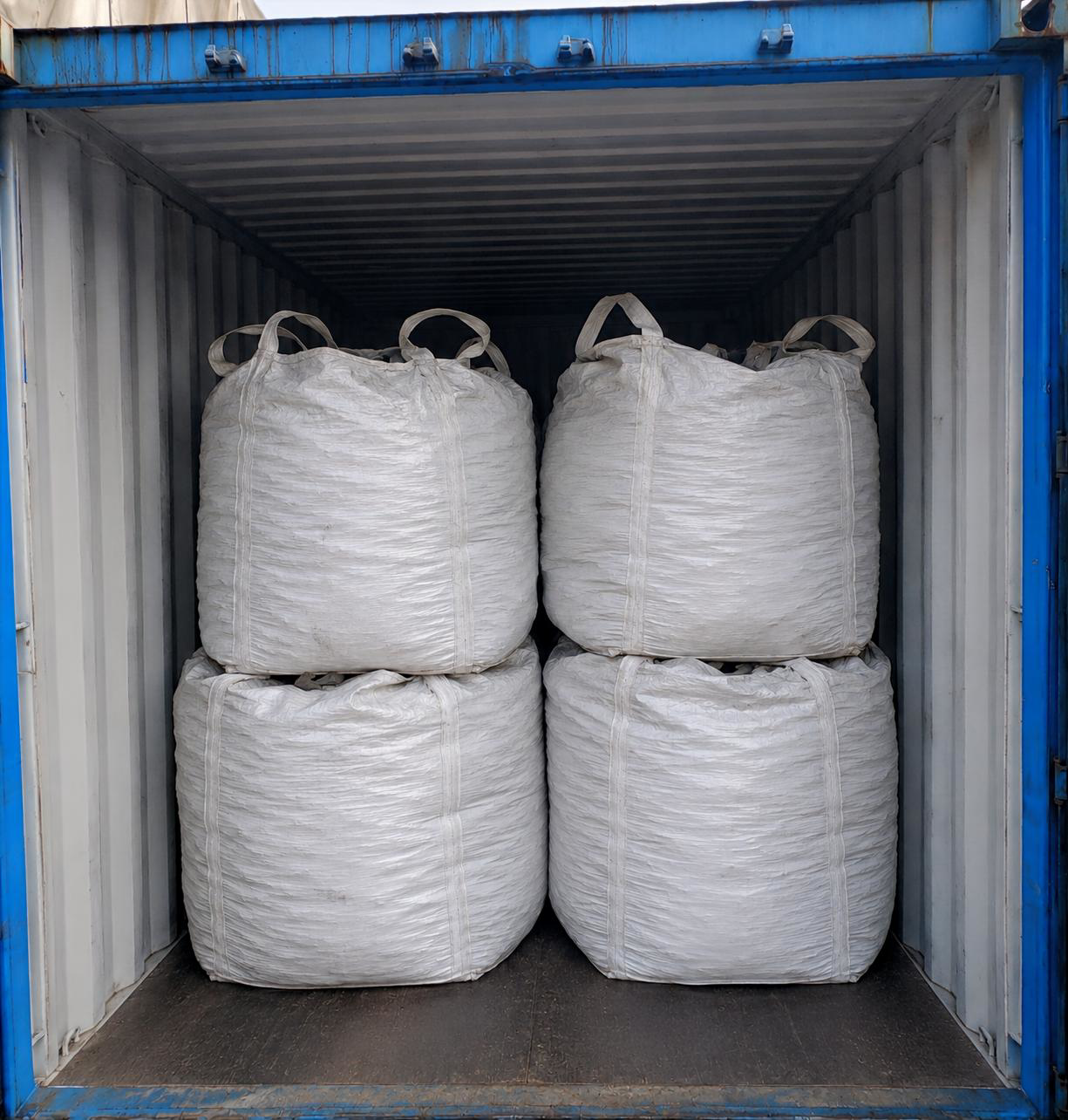 Four stacked white bulk bags in container